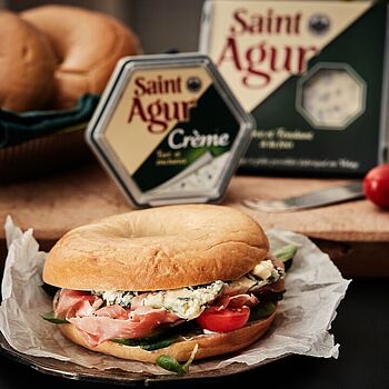 Als perfekter Snack eignet sich ein belegter Bagel mit Schinken, frischen Tomaten und Saint Agur